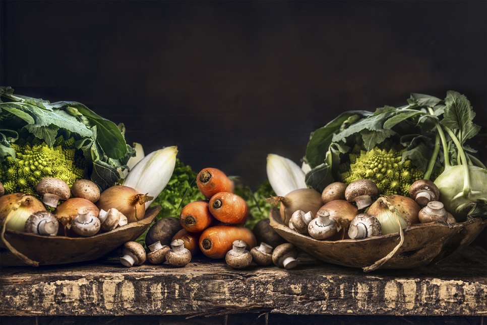 Des légumes (champignons, carottes, oigons, coux...) sur une vieille table en bois rustique
