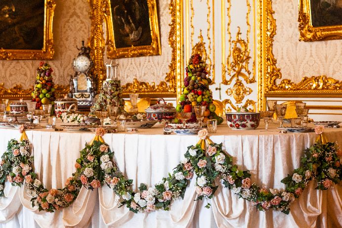 Photograph of a table staged to look like a Louis XIV banquet. Fruit has been piled into pyramidal towers.